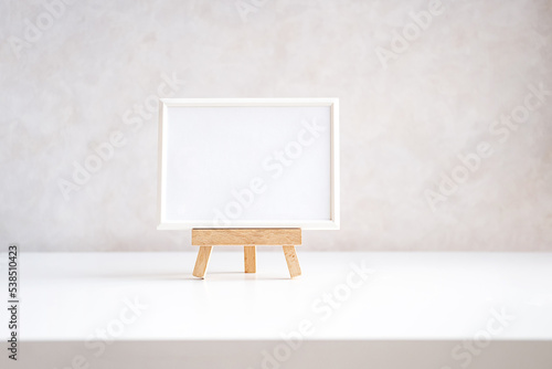 Fototapeta Naklejka Na Ścianę i Meble -  Empty picture frame mock up in minimalist interior on white table.