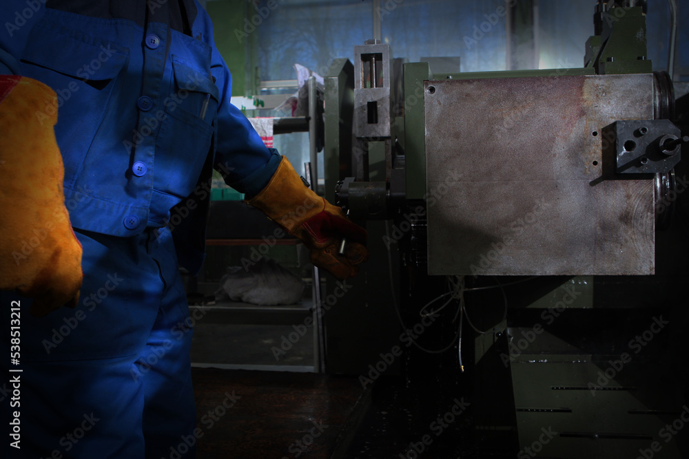 The worker controls the machine for the manufacture of bearings. Worker in the production of bearings. An unrecognizable personality. Harmful production. The worker controls the machine for the manufacture of bearings. Worker in the production of bearings. An unrecognizable personality. Harmful production.