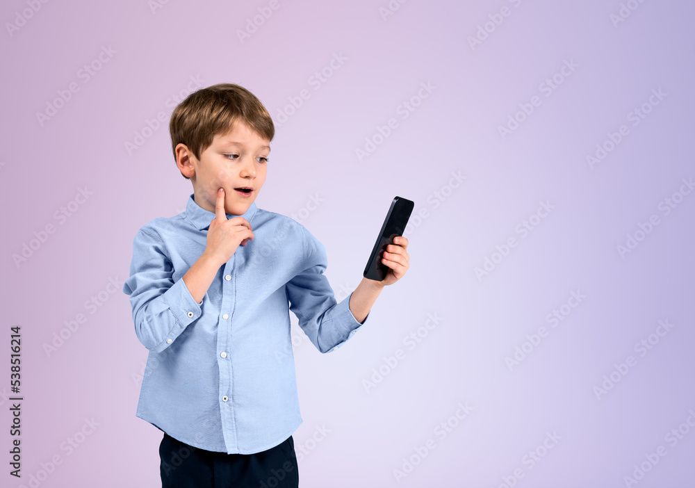 Boy using smartphone with pensive look, empty lilac copy space background Boy using smartphone with pensive look, empty lilac copy space background