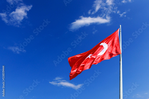 the flag of Turkey flutters against the blue sky with clouds. High quality photo