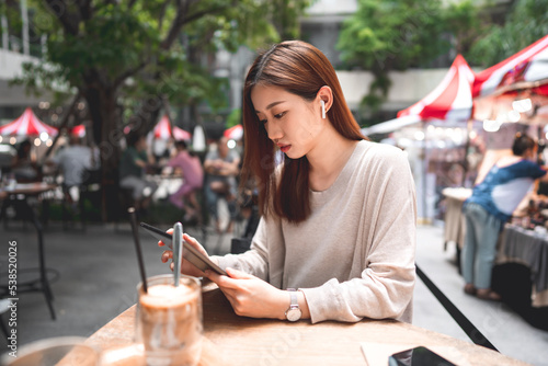 Business freelancer adult asian woman using digital tablet for work at sidewalk cafe