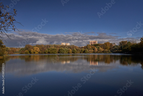 Pond surrounded by yellow trees in afternoon.