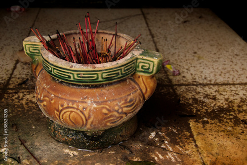 Clay pot filled with used up red incense sticks in an old khmer altar © MarieXMartin