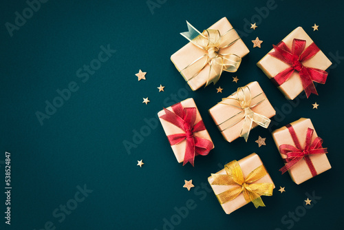Golden Christmas gift or present boxes and star confetti on blue backgroundn top view. Flat lay. photo
