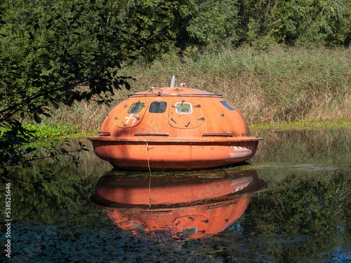 An orange rescue capsule or fully lockable lifeboat on the water photo
