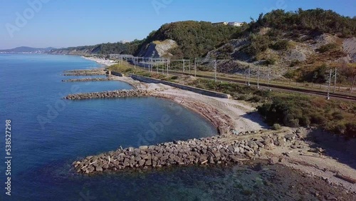 above the beaches with stone breakwaters near the railway station in the resort village near the Black Sea - aerial view on a sunny summer day photo