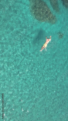 aerial view of joung man swiming on cristal clear waters on a beach of mallorca. Concept of holiday, summer, travel, tourism and relax 