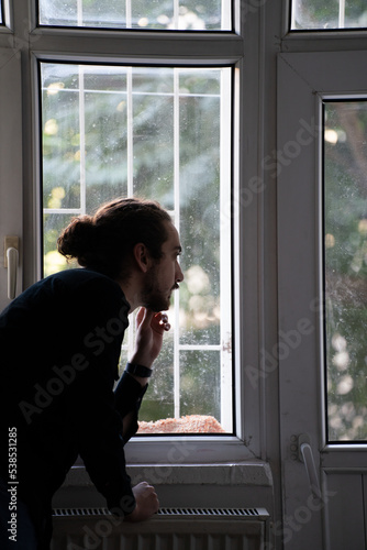 sad person watching outside from window