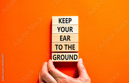 Keep your ear to the ground symbol. Concept words Keep your ear on the ground on wooden blocks. Businessman hand. Beautiful orange background. Business keep your ear on the ground concept. Copy space.
