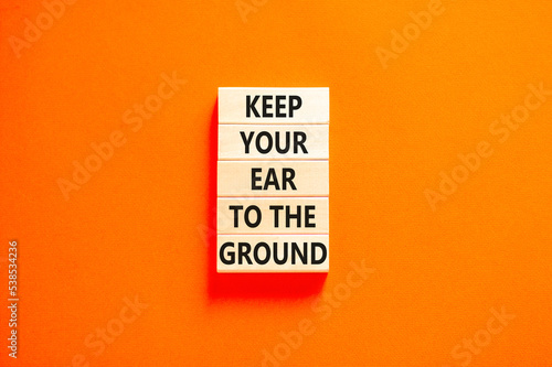 Keep your ear to the ground symbol. Concept words Keep your ear on the ground on wooden blocks. Beautiful orange table orange background. Business keep your ear on the ground concept. Copy space.