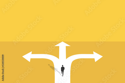businessman walk in front of a crossroad with road split in three different ways as arrows. photo