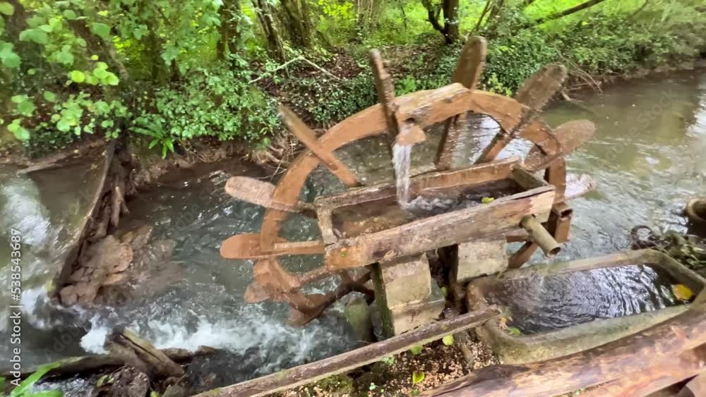 a hand built wooden water mill in operation raising water to irrigate the nearby crops a hand built wooden water mill in operation raising water to irrigate the nearby crops
