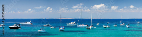 Panorama of a azure bay near Alicante resort with sea sailing yachts and boats  Spain. Wide panorama with coastline of Tabarca Island with many sailing ships and tourist at sea.