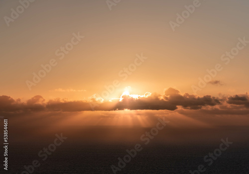Calm sea with sunset sky and sun through the clouds. Tranquil landscape and horizon over the water