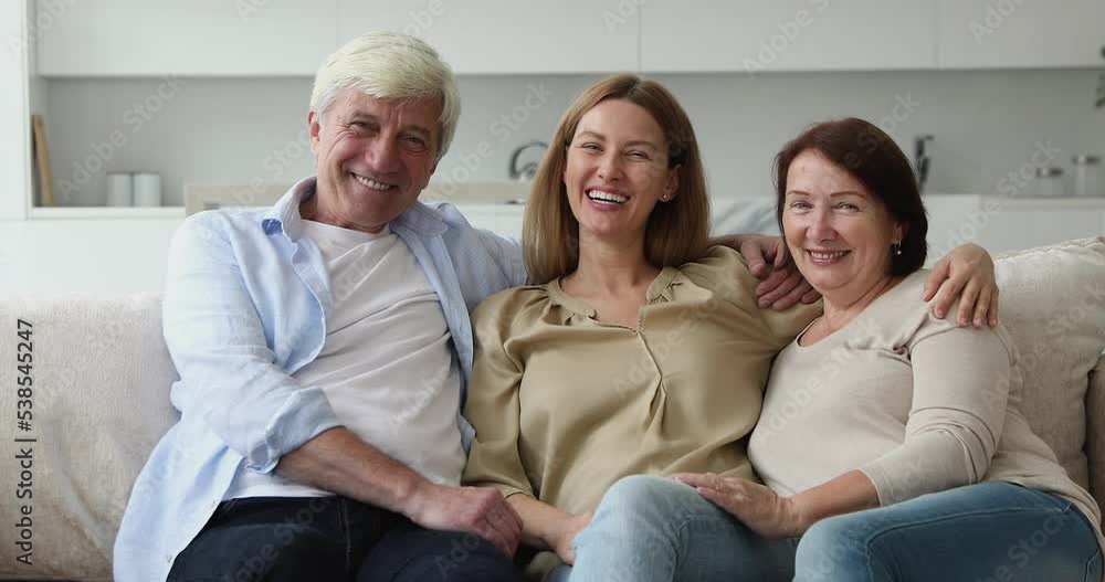 Multi-generational well-being family portrait concept. Beautiful young adult daughter resting on sofa laughing enjoy communication and leisure at modern home spend weekend with old mother and father Multi-generational well-being family portrait concept. Beautiful young adult daughter resting on sofa laughing enjoy communication and leisure at modern home spend weekend with old mother and father
