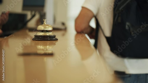 Hotel bell in focus and blurred guests checking in photo