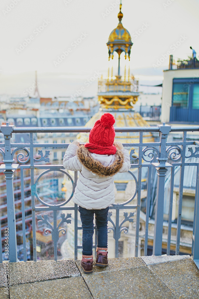 little girl enjoying view to Parisian skyline with roofs