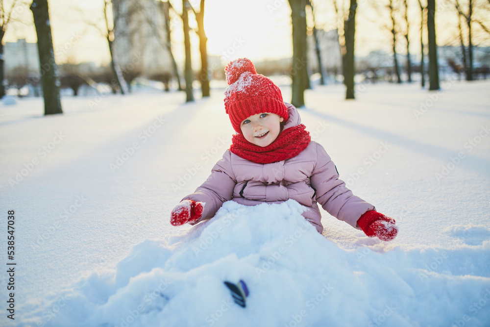 Adorable preschooler girl having fun in beautiful winter park on a snowy cold winter day Adorable preschooler girl having fun in beautiful winter park on a snowy cold winter day