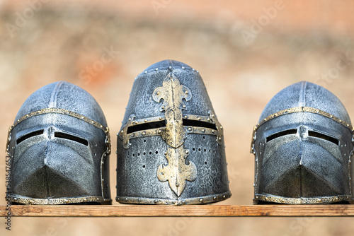 three medieval helmets over a wooden board