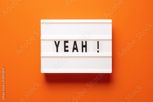 Fotografia Lightbox with word yeah on orange background, top view