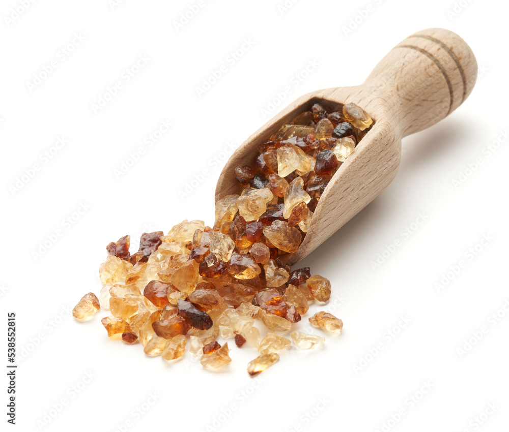 Obraz premium Cukier brązowy kandyzowany w drewnianej łopatce na białym tle