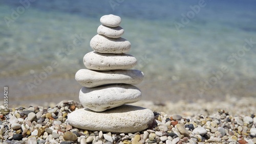 Small tower made of stones. The pebbles are stacked on top of each other. Stone pyramid on a background of water.