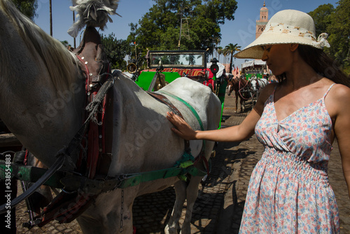 Beautiful tourist woman playing the horse of the carriage that is there in the Jmaa El Fna square, which is the main square and the most famous place in the Moroccan city of Marrakech.