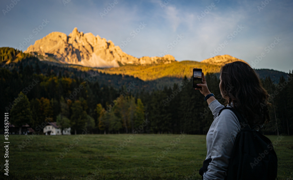 girl is taking a picture of the mountains, sunset time in Dolomites girl is taking a picture of the mountains, sunset time in Dolomites