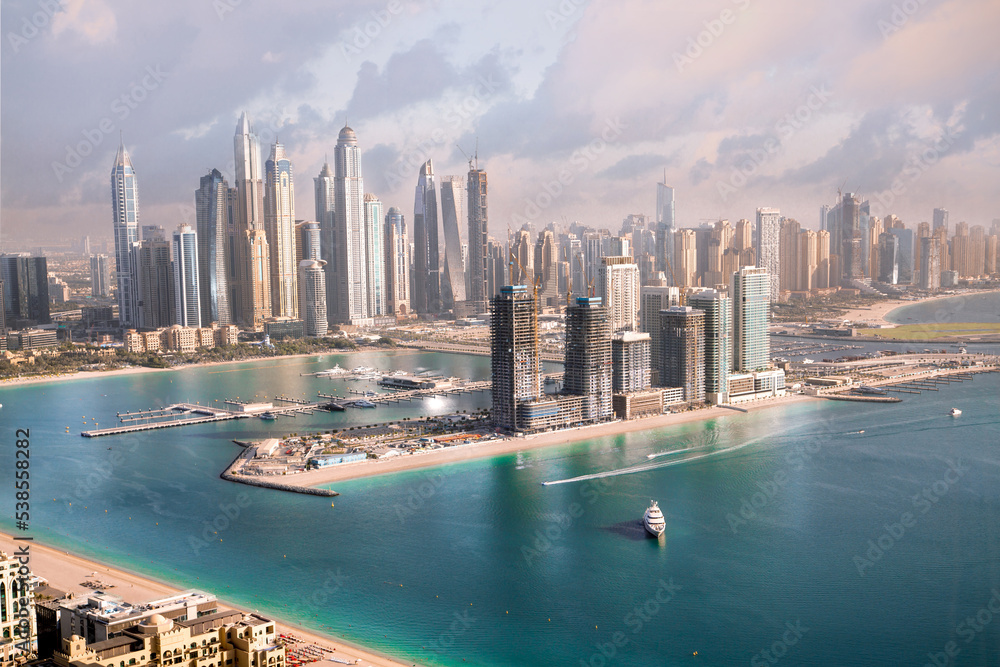 Obraz premium Dubai Marina skyscrapers complex of residential and office buildings at sunset. Yachts and speed boats in the gulf water. Dubai, UAE
