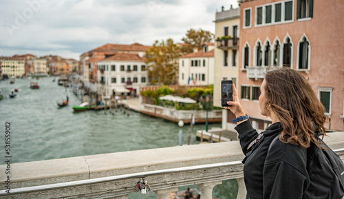 Tourist girl is taking a picture from Wikipedia Ponte delle Guglie in Venice
