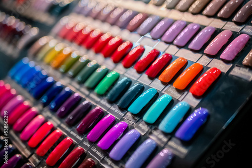 Set of multicolored palletes of gel nail polishes on counter of cosmetic store  manicure salon  exhibition - close up view. Fashion  care  cosmetic  beauty  glamour concept