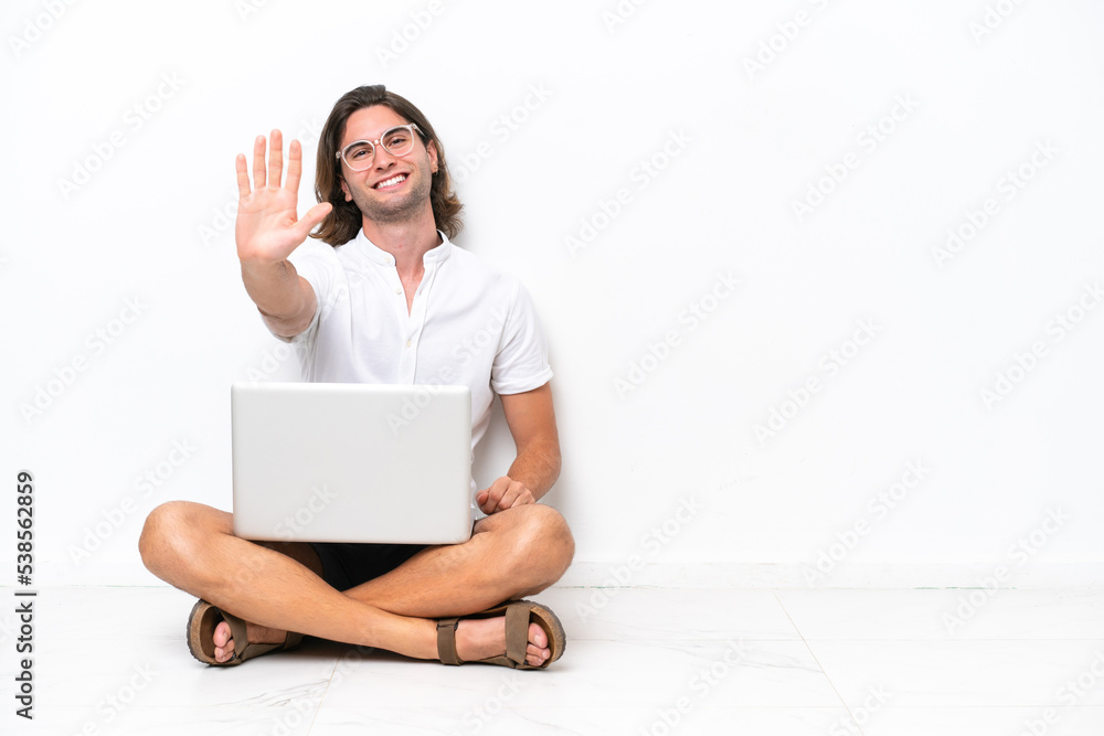 Young handsome man with a laptop sitting on the floor isolated on white background counting five with fingers Young handsome man with a laptop sitting on the floor isolated on white background counting five with fingers