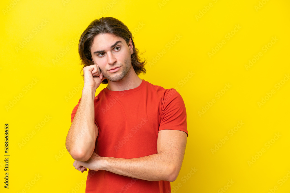 Caucasian handsome man isolated on yellow background with tired and bored expression Caucasian handsome man isolated on yellow background with tired and bored expression