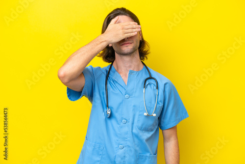Young surgeon caucasian man isolated on yellow background covering eyes by hands. Do not want to see something photo