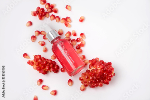 Composition with natural cosmetic oil and pomegranate on light background. 