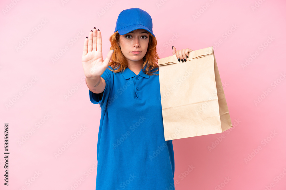 Young caucasian woman taking a bag of takeaway food isolated on pink background making stop gesture Young caucasian woman taking a bag of takeaway food isolated on pink background making stop gesture