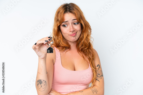Young caucasian woman holding home keys isolated on white background with sad expression