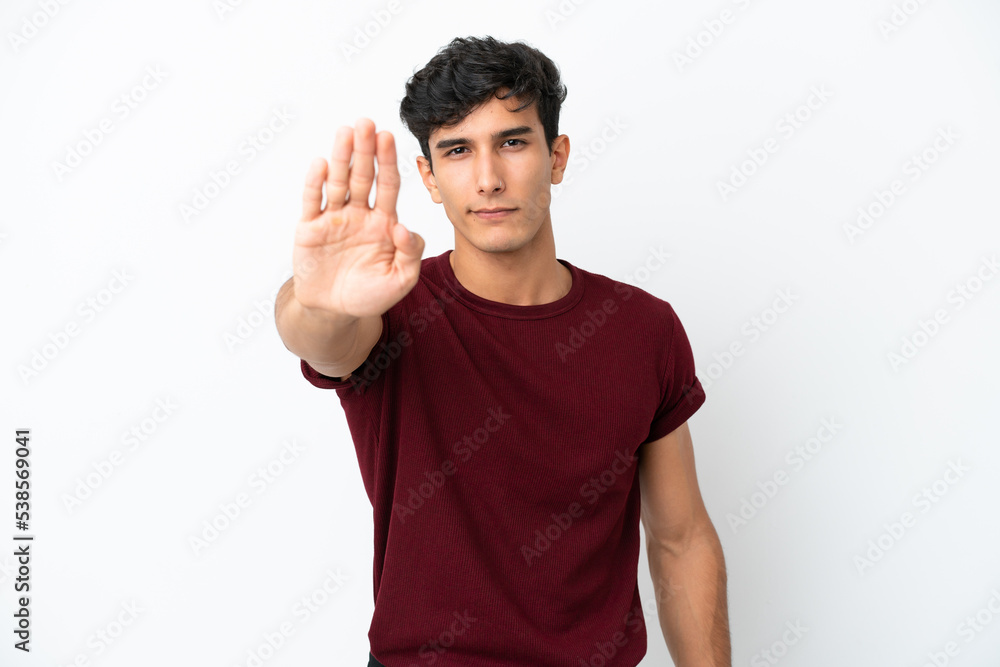 Young Argentinian man isolated on white background making stop gesture Young Argentinian man isolated on white background making stop gesture