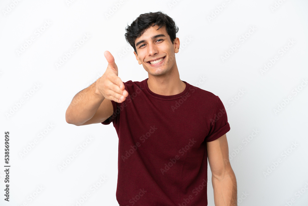 Young Argentinian man isolated on white background shaking hands for closing a good deal Young Argentinian man isolated on white background shaking hands for closing a good deal