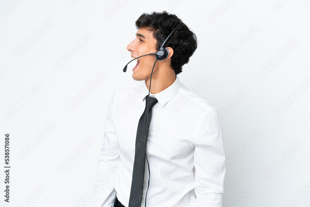 Telemarketer man working with a headset isolated on white background laughing in lateral position Telemarketer man working with a headset isolated on white background laughing in lateral position