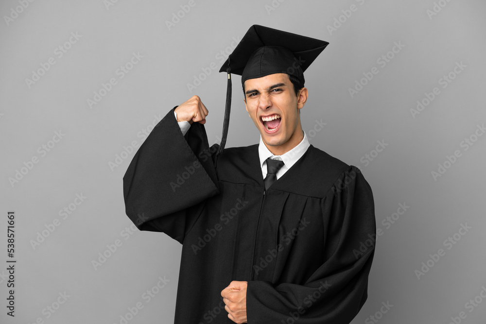 Young Argentinian university graduate isolated on grey background doing strong gesture Young Argentinian university graduate isolated on grey background doing strong gesture