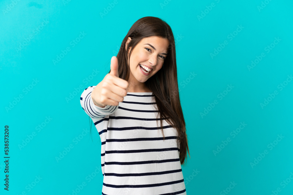 Teenager Brazilian girl over isolated blue background with thumbs up because something good has happened Teenager Brazilian girl over isolated blue background with thumbs up because something good has happened