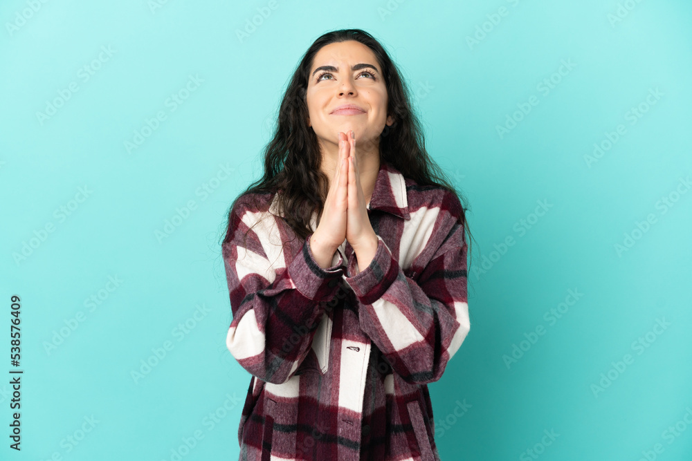 Young caucasian woman isolated on blue background keeps palm together. Person asks for something Young caucasian woman isolated on blue background keeps palm together. Person asks for something
