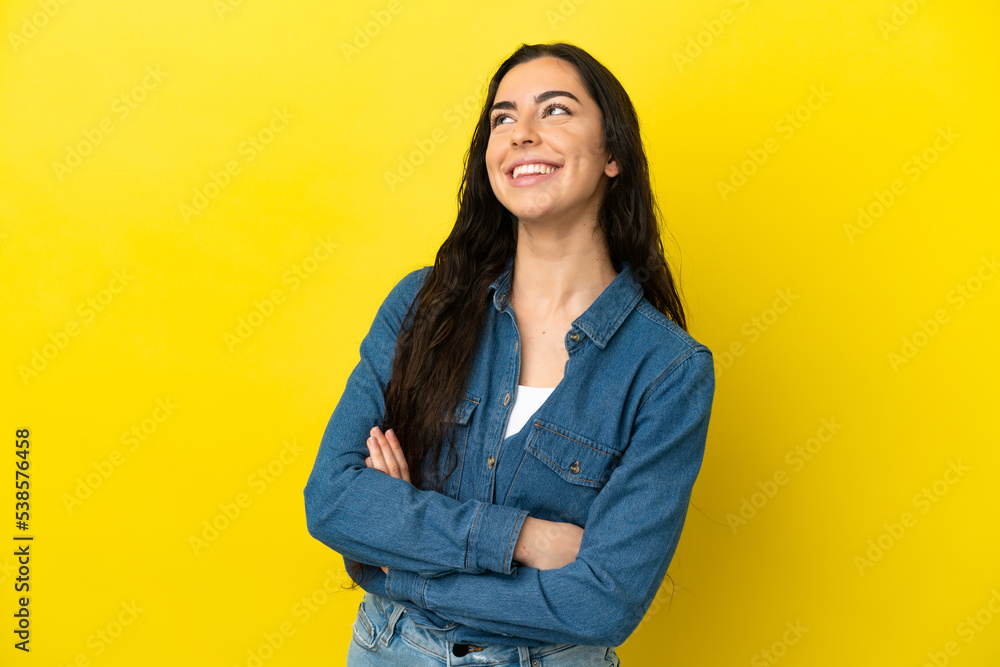 Young caucasian woman isolated on yellow background looking up while smiling Young caucasian woman isolated on yellow background looking up while smiling