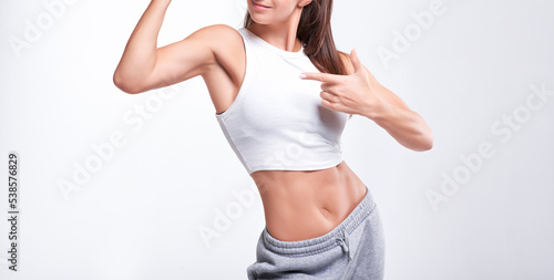 No name portrait. Young white fitness woman wearing sportswear standing over white wall background. Fitness concept