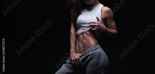 Athletic fitness woman posing in the studio on a dark background. Photo of an attractive woman in fashionable sportswear. Sports and healthy lifestyle