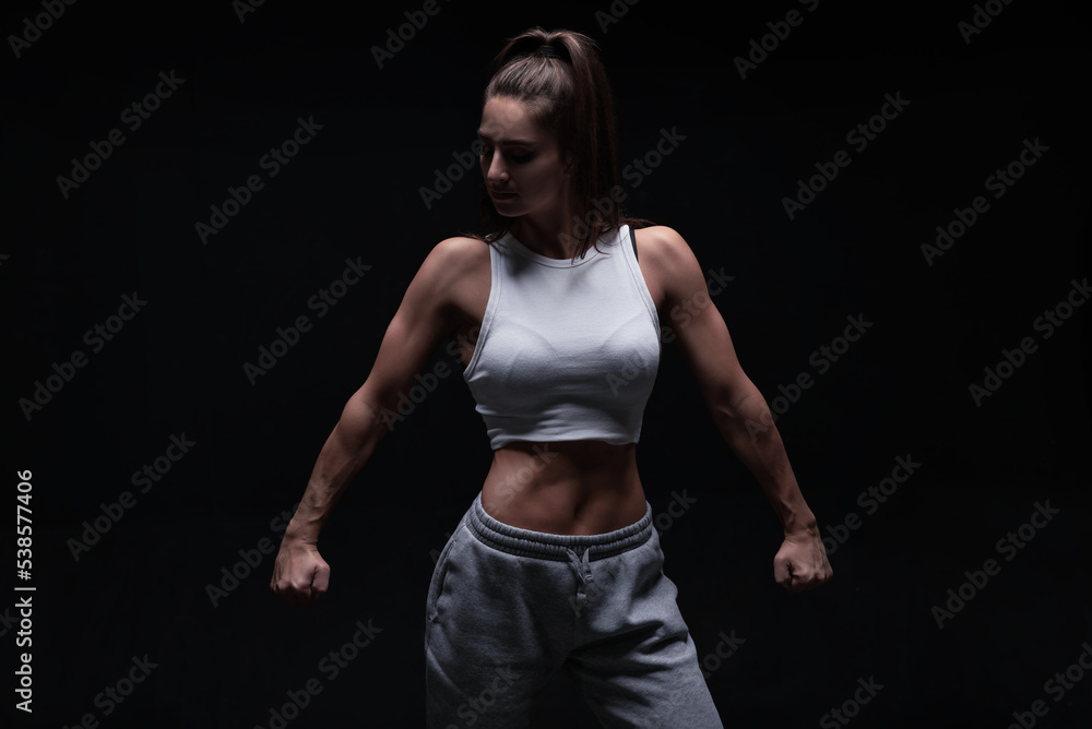 Athletic fitness woman posing in the studio on a dark background. Photo of an attractive woman in fashionable sportswear. Sports and healthy lifestyle