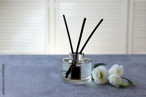Reed diffuser and eustoma flowers on gray marble table