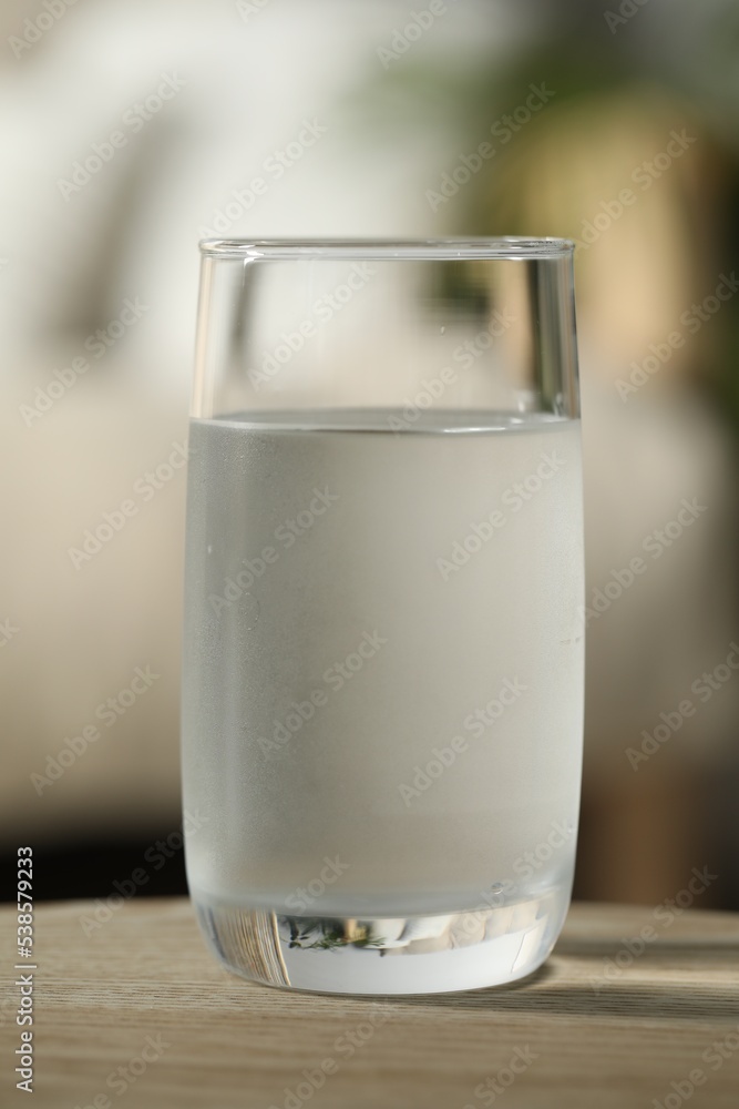 Glass of pure water on wooden table against blurred background, closeup Glass of pure water on wooden table against blurred background, closeup