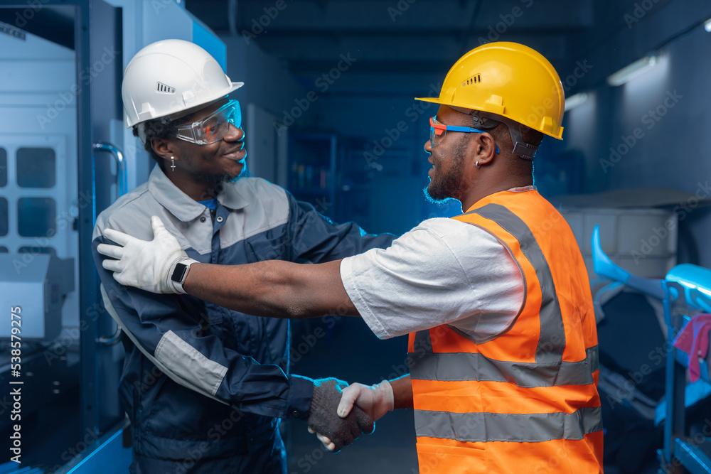 Teamwork in Industry factory. Engineer african Men workers shake hands background CNC equipment Teamwork in Industry factory. Engineer african Men workers shake hands background CNC equipment